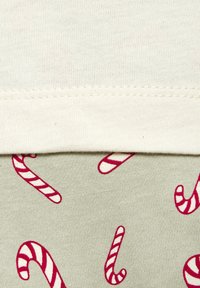 Lichtbeige katoenstof met een gladde textuur, bedekt met een groene stof met herhalende patronen van roze en witte gestreepte zuurstokken.