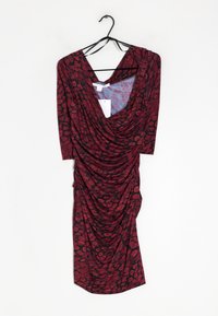 Robe à motif floral rouge et noir avec un devant drapé et des manches courtes, fabriquée en tissu doux et extensible ; suspendue à un crochet noir.