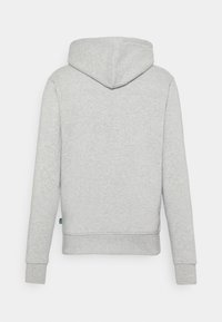 Felpa grigia con cappuccio, realizzata in un tessuto misto cotone, presenta un cappuccio, maniche lunghe, polsini e bordo a coste, texture morbida e una piccola etichetta con logo sul bordo.