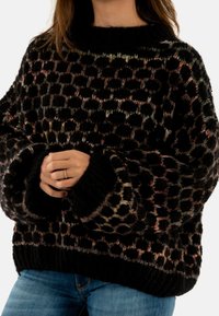Maglione nero a maglia con un motivo testurizzato di punti e rettangoli colorati. I polsini e l'orlo a coste aggiungono dettagli al fit morbido.