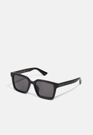 Melni kvadrātiņi saulesbrilles ar tumšiem stikliem. Rāmim ir matēta apdare ar zeltītu "GUCCI" zīmolu uz kājas. Izturīgs dizains ar leņķainām malām.