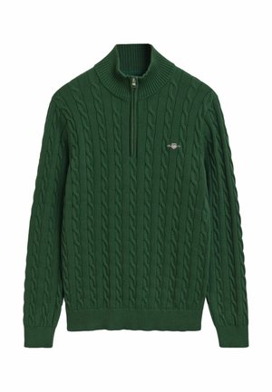 Pull en tricot vert avec col montant, présentant un motif en câble, une fermeture éclair au cou et un petit logo sur la poitrine gauche.