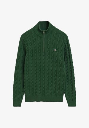 Pull en tricot vert avec col montant, présentant un motif en câble, une fermeture éclair au cou et un petit logo sur la poitrine gauche.