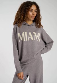 Grauer Hoodie aus weichem Material mit der Aufschrift "MIAMI" in cremefarbener Schrift, lässiger Schnitt, langen Ärmeln und einer Kapuze mit Kordelzug.