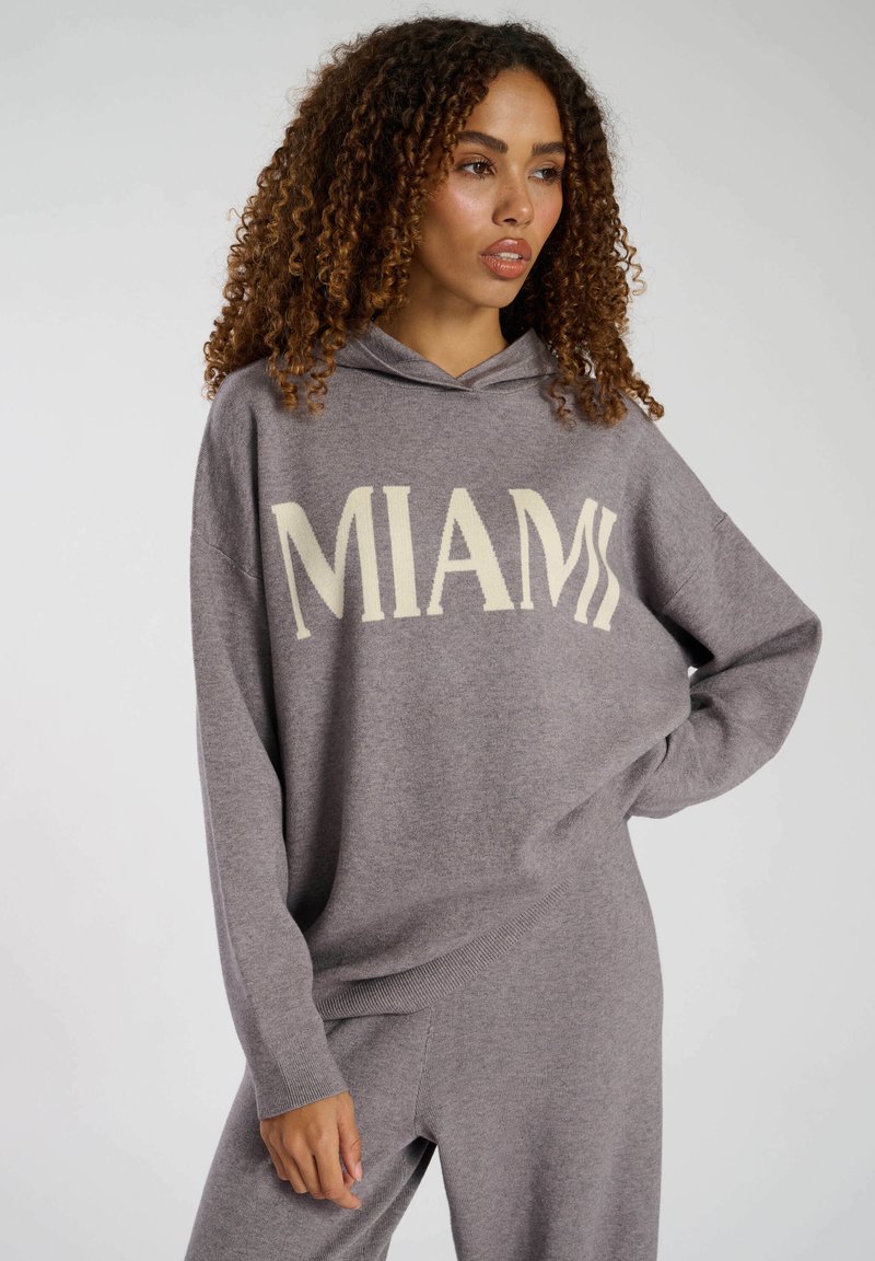 Grauer Hoodie aus weichem Material mit der Aufschrift "MIAMI" in cremefarbener Schrift, lässiger Schnitt, langen Ärmeln und einer Kapuze mit Kordelzug.