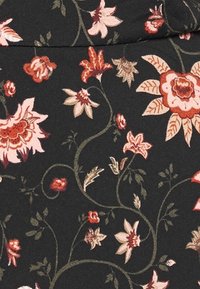 Musta kangas, jossa on kukkakuvio, sisältäen vaaleanpunaisia, punaisia ja kermaisia kukkia, ja vihreitä köynnöksiä, luoden tekstuurisen ulkonäön.