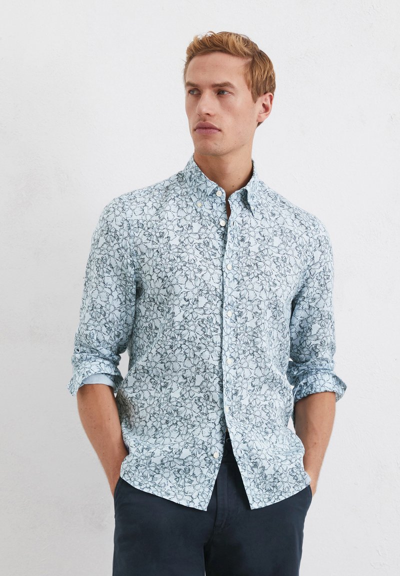 Camicia azzurro chiaro con motivo floreale, maniche lunghe arrotolate fino ai gomiti e una texture morbida. Vestibilità slim con colletto e chiusura a bottoni.