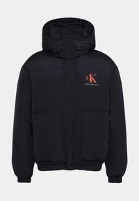Svart puffjacka med hög krage, två framfickor, elastiska muddarna och Calvin Klein Jeans-logotyp i orange på vänster bröst.