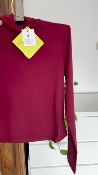 Top a maniche lunghe di colore bordeaux realizzato in tessuto morbido ed elastico. Presenta un collo alto e un'etichetta attaccata con le istruzioni per la cura.