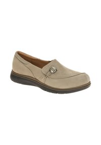 Beige slip-on shoe made of suede, featuring stitching details, a decorative buckle, and a black rubber sole for grip and comfort.