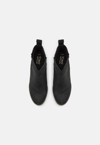 Bottines en cuir noir avec une texture lisse, un bout pointu et des panneaux latéraux élastiques. Comprend une languette à l'arrière et une semelle plate.
