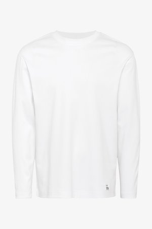 T-shirt blanc à manches longues en coton, avec un col rond et une petite étiquette noire avec "73" à l'ourlet. Texture lisse.