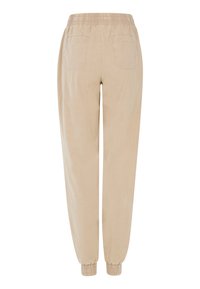 Beige Baumwoll-Jogginghosen mit einem elastischen Bund, zwei Gesäßtaschen und schmalen Bündchen an den Knöcheln. Glatte Textur, entspannte, schmal zulaufende Passform.
