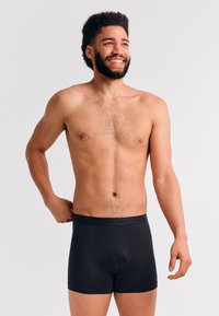 Schwarze Boxershorts aus glattem Stoff, mit einem weichen Bund und dezenter Markenkennzeichnung, taillierter Passform und mittellangen Beinen.