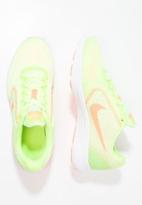 Baskets en maille vert fluo avec des accents orange, bout rond et semelle texturée. Dotées de lacets plats et d'un col rembourré pour le confort.