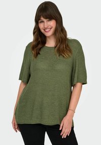 Žalias trumpas rankovės megztas marškinėliai su apvalia iškirpte, laisvas siluetas ir tekstūruota medžiaga, derinami su juodomis kelnėmis.