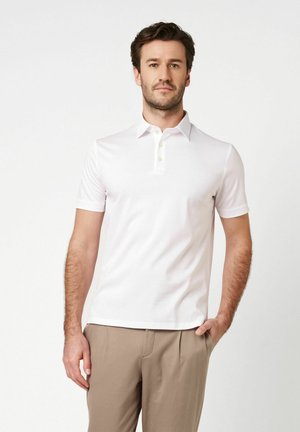 Kurzärmeliges, weißes Poloshirt mit Kragen, ausgestattet mit einer Drei-Knopf-Leiste und glatter Textur, getragen zu hellbeigen Hosen.