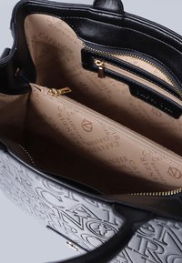 Borsa nera con lettering in rilievo, interno beige, cerniere dorate e più scomparti, compreso un taschino con cerniera.