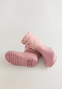 Stivali impermeabili rosa con parte superiore trapuntata, parte inferiore in gomma e suola testurizzata. Presentano un design con lacci e dettagli in metallo.