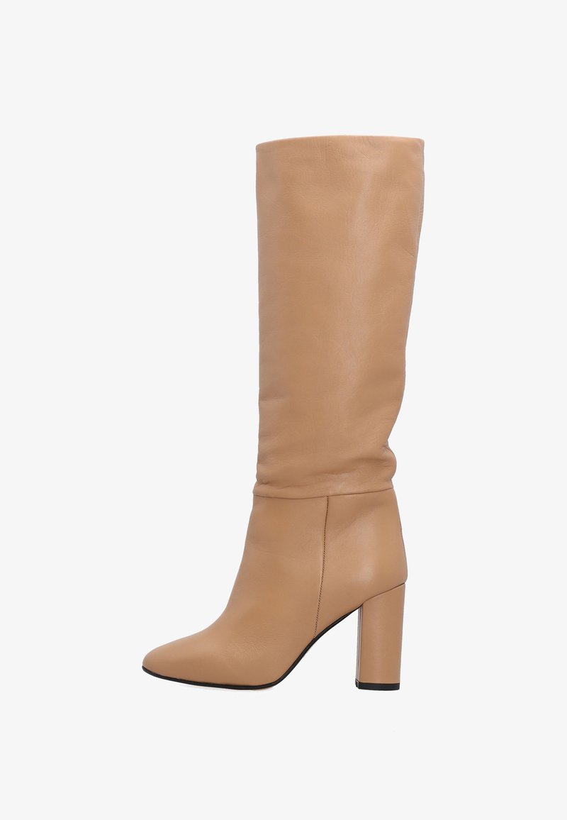 Beige leren laars tot de knie met een spitse neus en een dikke blokhak. Glad materiaal met een lichtjes verslapen ontwerp aan de bovenste schacht.