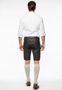 Kožené šortky s úzkým střihem, černé barvy, s dekorativním prošíváním a jednou boční kapsou. V kombinaci s pletenými ponožkami do půli lýtek.