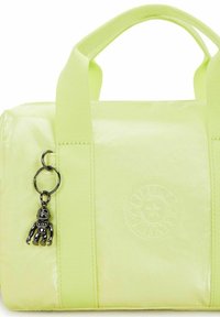 Kirkas keltainen olkalaukku, jossa on kiiltävä pinta, kangaskahvat, kohokuvioitu logo ja metallinen charm, joka on pienen apinan muotoinen.