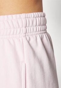 Lyserøde sweatpants med elastisk talje, der har en glat bomuldsstruktur og sidelommer.