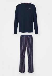 Mørkeblå langærmet pyjamashirt med logo på brystet, parret med stribede bukser i mørkeblå, rød og hvid med elastisk talje.