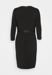 Robe noire à manches trois-quarts, coupe ajustée, avec une ceinture noire brillante accentuant la taille. Fermeture éclair incrustée au dos. Tissu lisse.