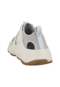 Scarpa da ginnastica grigia chiara e bianca con tomaia in rete, suola texturizzata e un linguetta blu sul tallone. Presenta un design con ritagli per la ventilazione.