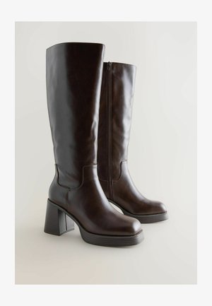 Brune læderknæhøje støvler med rund tå, blokhæle og lynlås i siden. Glat tekstur med subtile syninger.