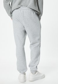 Lys grå sweatpants med elastisk talje og mansjetter, der har en blød tekstur og sidelommer. Sættes sammen med hvide sneakers.