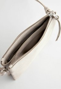 Clutch bag in suede beige con due scomparti con zip e una sottile tracolla annodata. Presenta accessori in tonalità argento e una texture liscia.