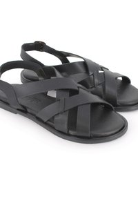 Sandalias de cuero negro con tiras entrecruzadas, parte trasera abierta, suela plana y textura suave. Construcción duradera para un uso cómodo.