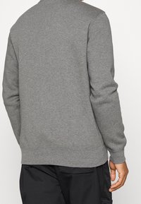 Šedá mikina vyrobená z měkké směsi bavlny, s dlouhými rukávy, žebrovanými manžetami a obepnutým pasem, s jednoduchou a hladkou texturou.