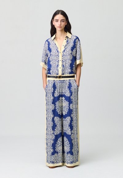 Completo due pezzi blu navy con intricati motivi paisley color crema. Camicia a maniche corte con colletto, pantaloni larghi e cintura abbinata.