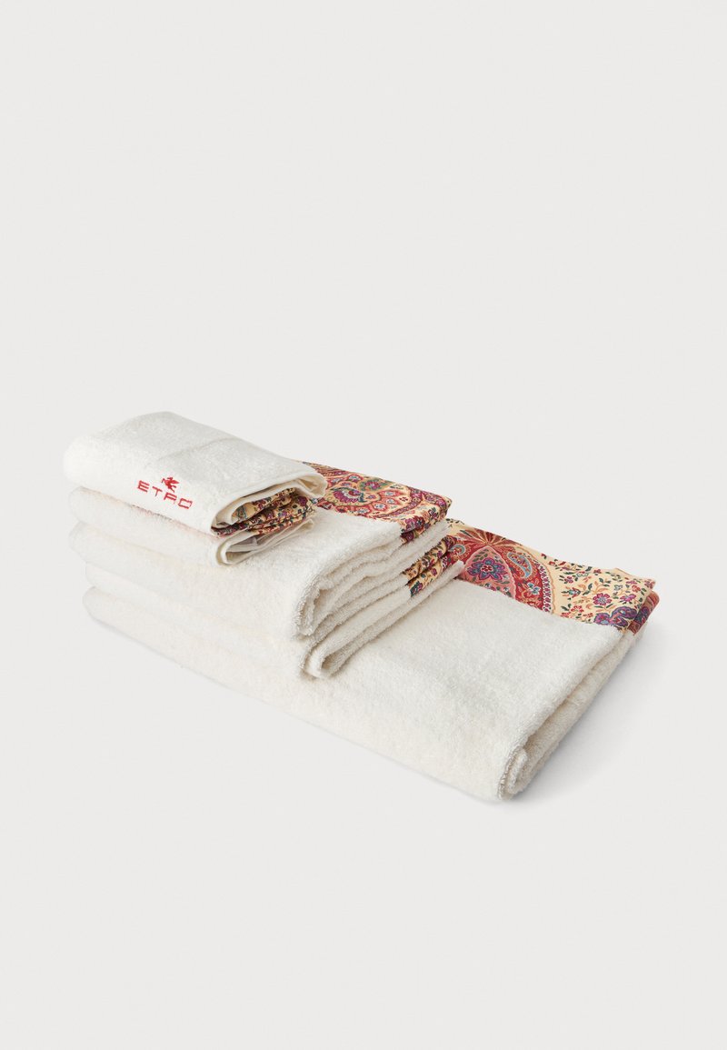 Pile de serviettes blanches avec bords pliés présentant des motifs cachemire colorés et un logo texte brodé rouge dans le coin supérieur de la serviette.