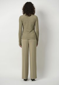 Khaki textuur trui met lange mouwen, gecombineerd met lichte khaki wijde broek, met een aansluitend ontwerp van achteren.