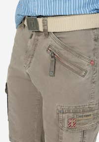 Beige cargo shorts made of cotton blend, featuring a zipper pocket with red accents, and a TIMEZONE logo patch on the side.