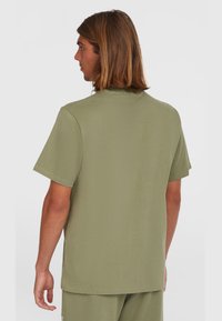 Camiseta de manga corta en verde oliva, confeccionada con algodón suave, con cuello redondo y un diseño de corte recto con detalles de costura mínimos.