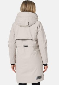 Lange, lichtbeige parka met een grote capuchon, een cinched taille en een logo patch. Heeft een gewatteerd bovenrug en een glad, waterdicht textuur.