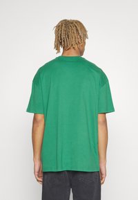 Grøn, kortærmet t-shirt lavet af bomuld, med en afslappet pasform og en rund halsudskæring. Enkelt design, minimal detaljer.