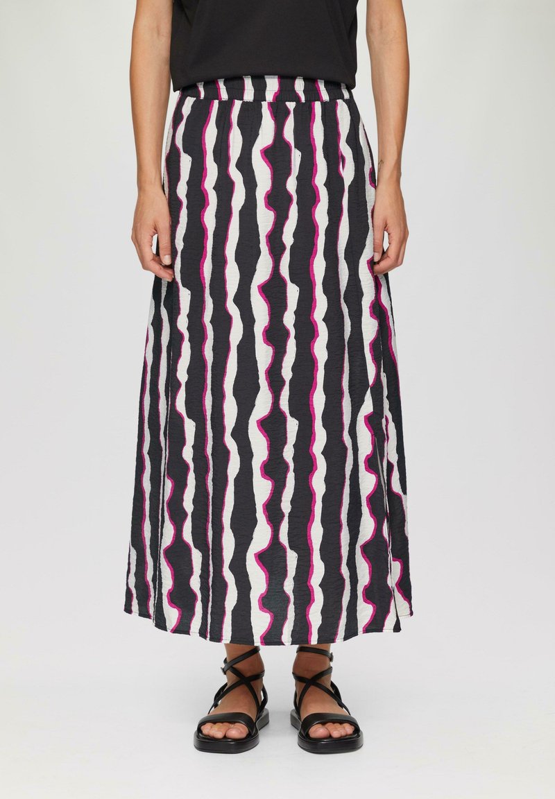 Maxi rok in zwart, wit en roze golvende strepen. Elastaanband, lichtgewicht stof en rechte snit, gecombineerd met zwarte sandaaltjes met bandjes.