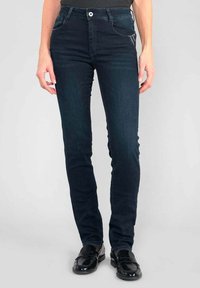 Jeans skinny de color azul oscuro hechos de denim, con una cintura de altura media, bolsillos frontales y un diseño clásico de cinco bolsillos. Textura suave.
