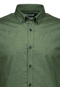 Grøn skjorte med knap-front, der har en struktureret krave, sorte knapper og et glat, tekstureret stof. Designet fokuserer på funktionalitet og komfort.