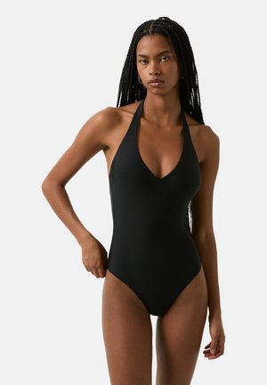 Maillot de bain d'une pièce noir avec un col halter, un décolleté en V profond et des jambes à hauteur élevée. Fabriqué à partir d'un tissu lisse et extensible pour plus de confort.