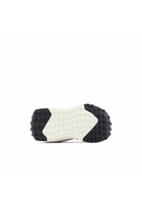 Semelle d'une chaussure avec une semelle extérieure en caoutchouc noir texturé et une semelle intermédiaire blanche, dotée de motifs ronds distinctifs pour une meilleure adhérence.