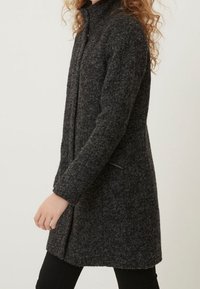 Mischwollmantel in Dunkelgrau, mit hohem Kragen, langen Ärmeln und seitlichen Reißverschlusstaschen. Strukturierte Oberfläche mit taillierter Silhouette.