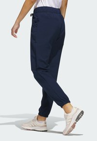 Mørkeblå joggebukser lavet af blødt stof, med elastisk talje, sidelommer og elastiske manchetter ved anklerne.
