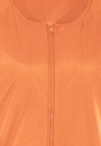 Lichtgewicht oranje jack met een rits aan de voorkant, geribbelde kraag en een gladde textuur. Heeft een casual ontwerp dat geschikt is voor verschillende gelegenheden.